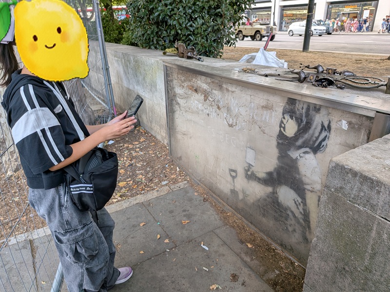 レモンがマーブルアーチ近くの少女の写真を撮っているところ。レモンのすぐ後ろにフェンスあり。